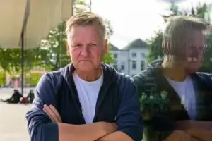 Jan CU Glas Musis Reflectie 3 - salomons.nl man leunend tegen glazen raam met zijn spiegelbeeld erin