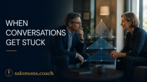 Two professionals in a coaching session discuss a stuck conversation, with a glowing pyramid diagram between them; 'When Conversations Get Stuck' text on dark blue background.